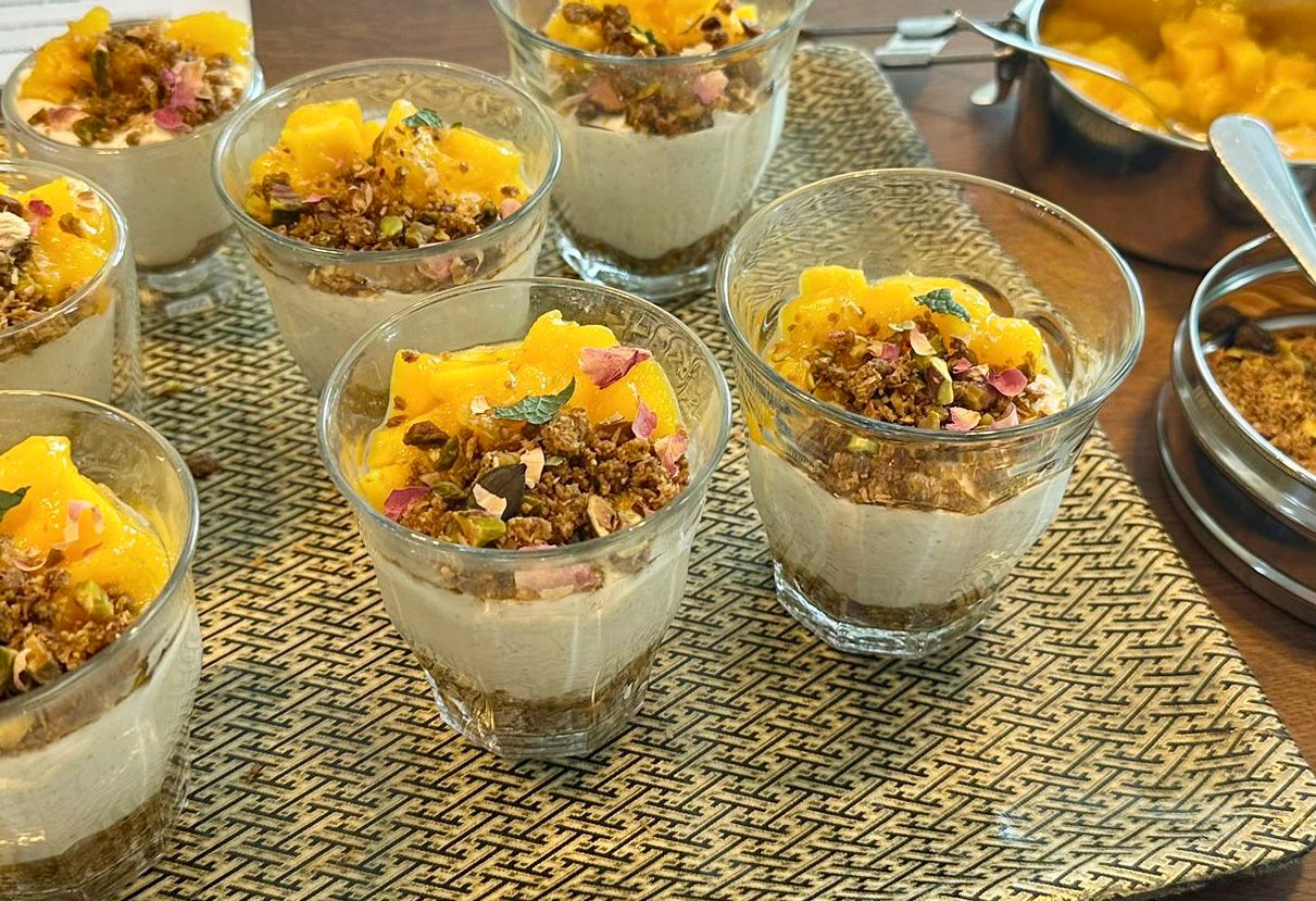 Small glasses layered with mango-saffron mousse, pistachio-coconut crumble, fresh mango and rose petals