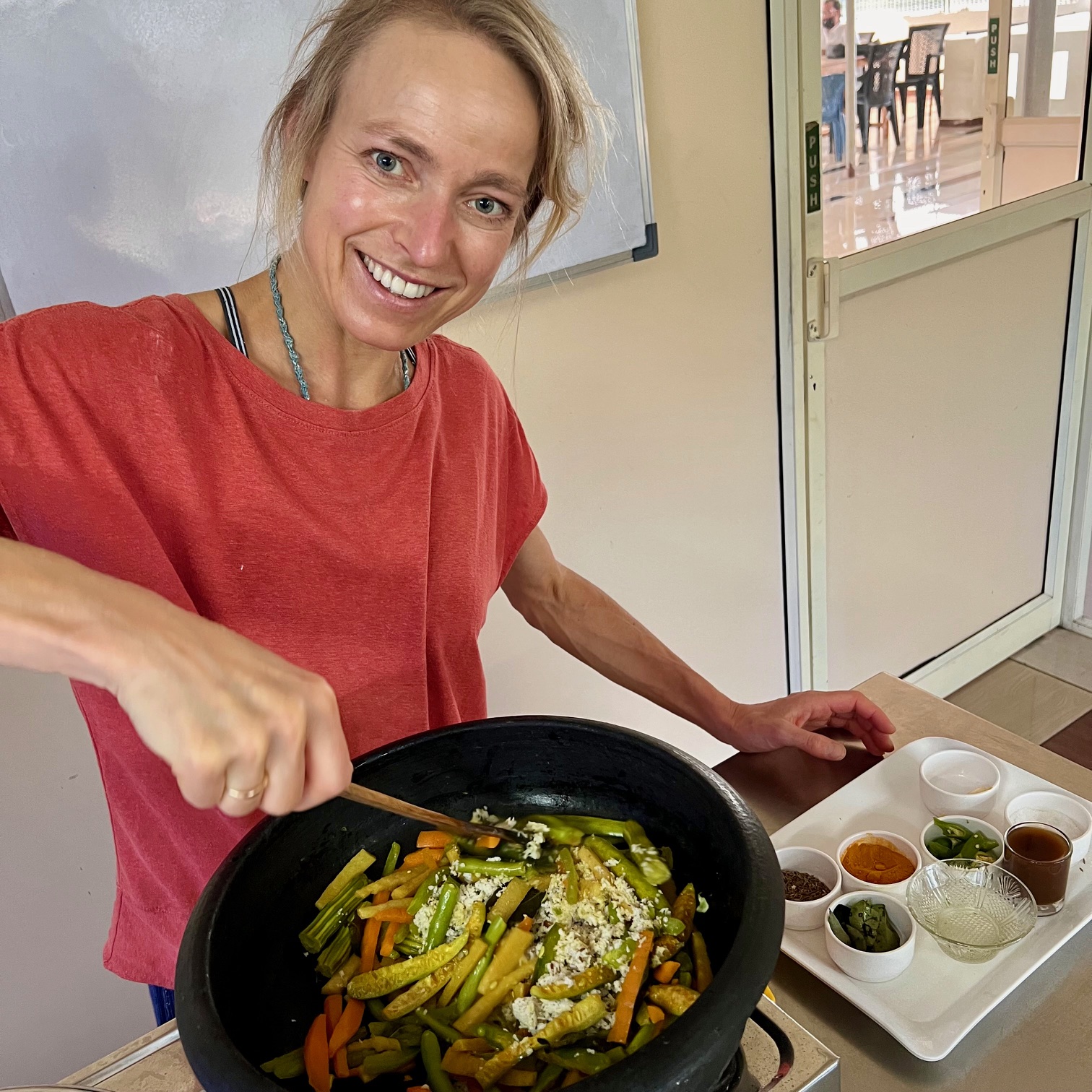 Hanna cooking at an Ayurvedic cooking workshop, laughing over a wok of vegetables
